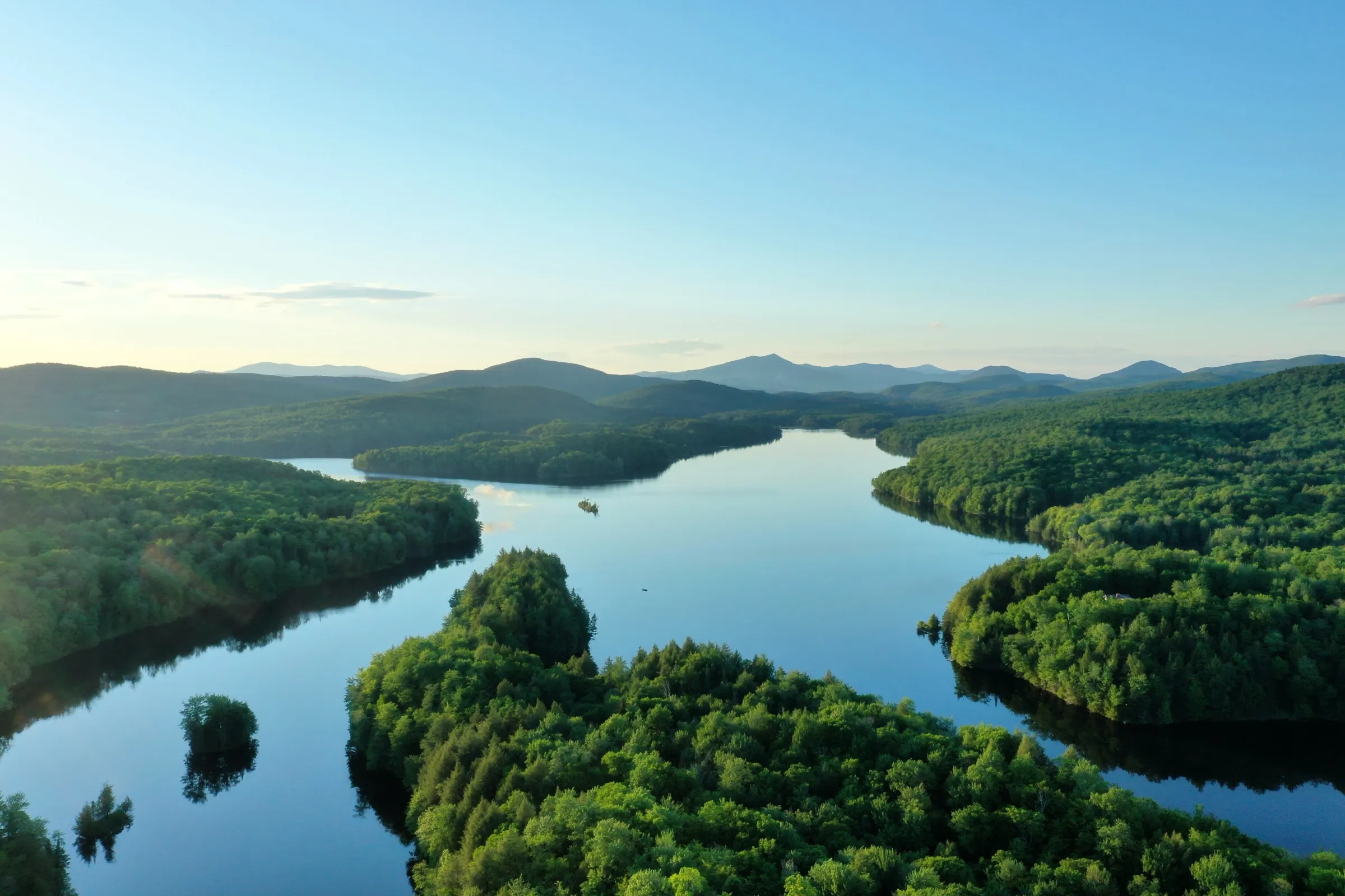 A river corridor winding through forested hills toward distant mountains